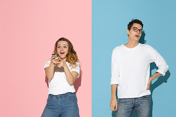 Image showing Young emotional man and woman on pink and blue background