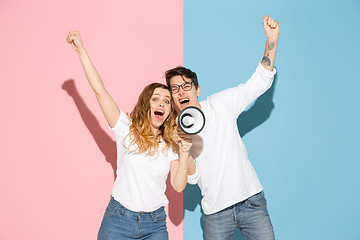 Image showing Young emotional man and woman on pink and blue background