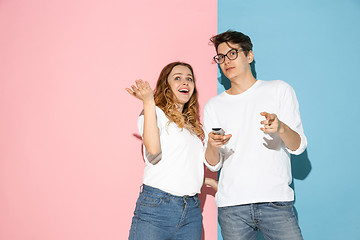 Image showing Young emotional man and woman on pink and blue background