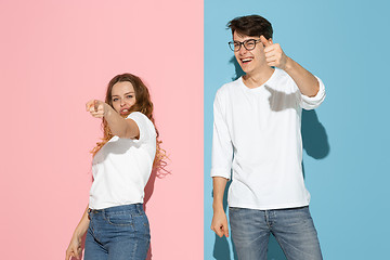 Image showing Young emotional man and woman on pink and blue background