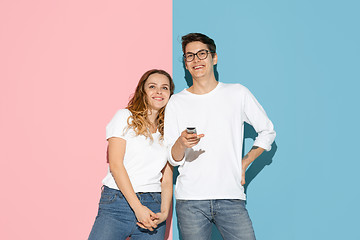 Image showing Young emotional man and woman on pink and blue background