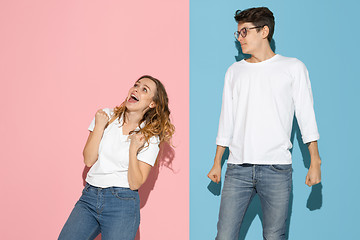 Image showing Young emotional man and woman on pink and blue background