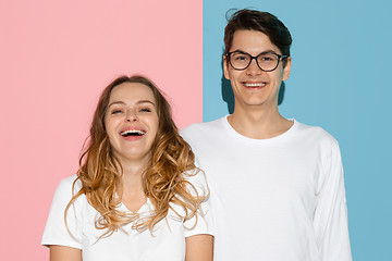 Image showing Young emotional man and woman on pink and blue background