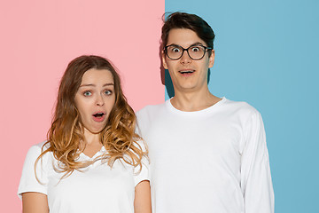 Image showing Young emotional man and woman on pink and blue background