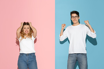 Image showing Young emotional man and woman on pink and blue background