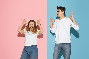 Image showing Young emotional man and woman on pink and blue background