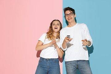 Image showing Young emotional man and woman on pink and blue background