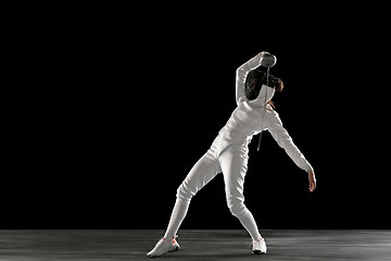 Image showing Teen girl in fencing costume with sword in hand isolated on black background