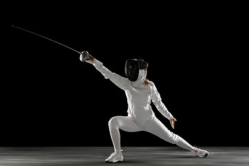 Image showing Teen girl in fencing costume with sword in hand isolated on black background