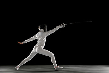 Image showing Teen girl in fencing costume with sword in hand isolated on black background