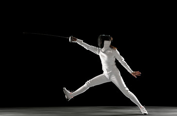 Image showing Teen girl in fencing costume with sword in hand isolated on black background