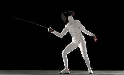 Image showing Teen girl in fencing costume with sword in hand isolated on black background