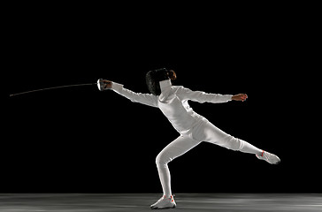 Image showing Teen girl in fencing costume with sword in hand isolated on black background