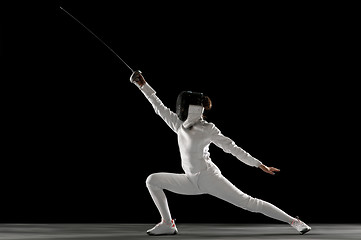 Image showing Teen girl in fencing costume with sword in hand isolated on black background