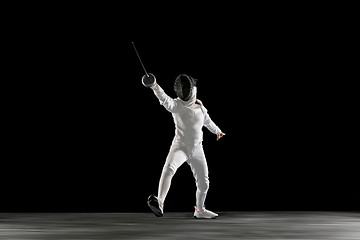 Image showing Teen girl in fencing costume with sword in hand isolated on black background