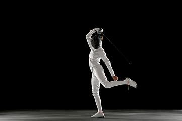 Image showing Teen girl in fencing costume with sword in hand isolated on black background