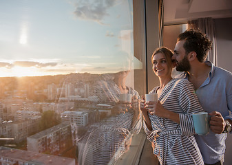 Image showing young couple enjoying evening coffee by the window