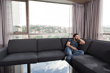 Image showing young casual man using a mobile phone at home