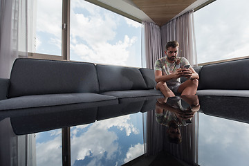 Image showing young casual man using a mobile phone at home