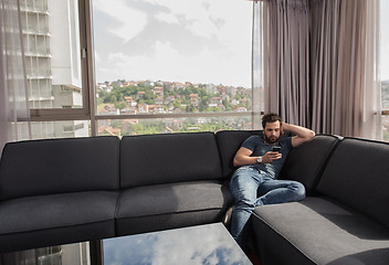 Image showing young casual man using a mobile phone at home