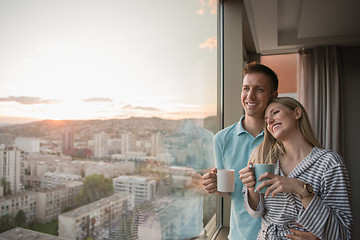 Image showing young couple enjoying evening coffee by the window