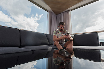 Image showing young casual man using a mobile phone at home