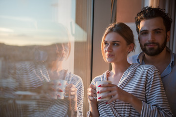 Image showing young couple enjoying evening coffee by the window