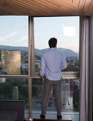 Image showing young man enjoying evening coffee by the window