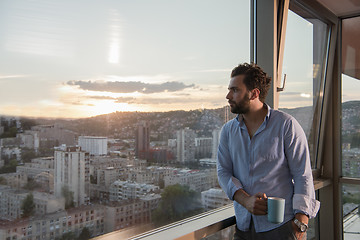 Image showing young man enjoying evening coffee by the window