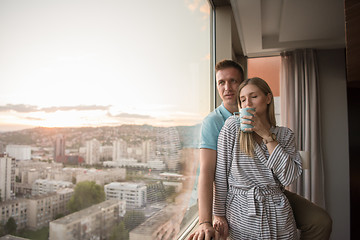 Image showing young couple enjoying evening coffee by the window