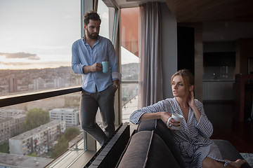 Image showing young couple enjoying evening coffee by the window