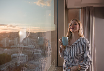 Image showing young woman enjoying evening coffee by the window