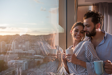 Image showing young couple enjoying evening coffee by the window