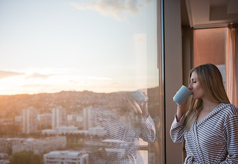 Image showing young woman enjoying evening coffee by the window