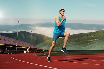 Image showing man running in the track. Fit male fitness runner jogging in stadium