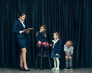 Image showing Cute stylish children on dark studio background. The beautiful teen girls and boy standing together