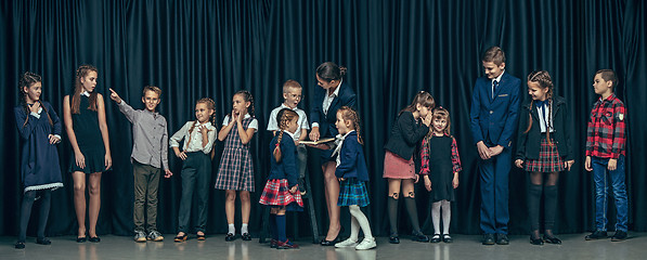 Image showing Cute stylish children on dark studio background. The beautiful teen girls and boy standing together