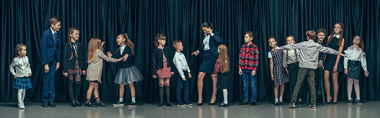 Image showing Cute stylish children on dark studio background. The beautiful teen girls and boy standing together