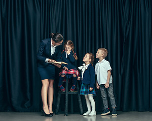 Image showing Cute stylish children on dark studio background. The beautiful teen girls and boy standing together