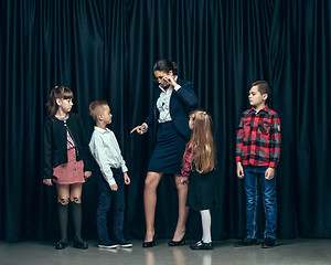 Image showing Cute stylish children on dark studio background. The beautiful teen girls and boy standing together