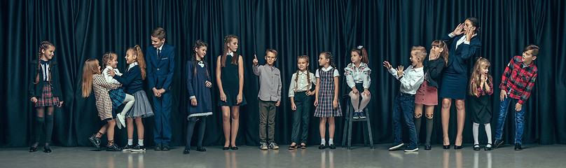 Image showing Cute stylish children on dark studio background. The beautiful teen girls and boy standing together