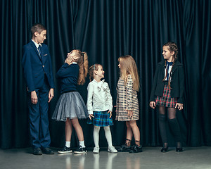 Image showing Cute stylish children on dark studio background. The beautiful teen girls and boy standing together