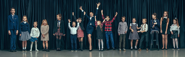 Image showing Cute stylish children on dark studio background. The beautiful teen girls and boy standing together