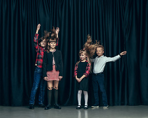 Image showing Cute stylish children on dark studio background. The beautiful teen girls and boy standing together