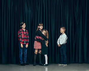 Image showing Cute stylish children on dark studio background. The beautiful teen girls and boy standing together