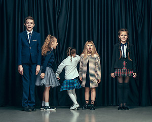 Image showing Cute stylish children on dark studio background. The beautiful teen girls and boy standing together