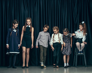 Image showing Cute stylish children on dark studio background. The beautiful teen girls and boy standing together