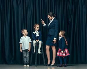 Image showing Cute stylish children on dark studio background. The beautiful teen girls and boy standing together