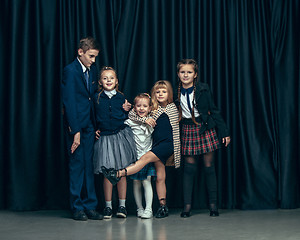 Image showing Cute stylish children on dark studio background. The beautiful teen girls and boy standing together