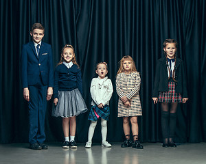 Image showing Cute stylish children on dark studio background. The beautiful teen girls and boy standing together